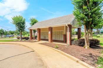 a small building with a sidewalk and trees in front of it
